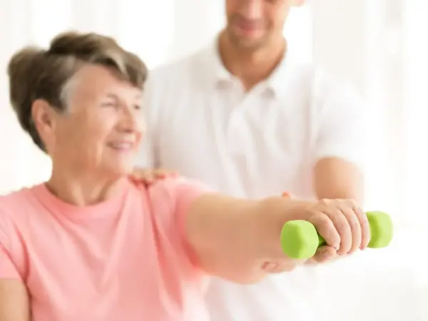 starsza kobieta ćwicząca z fizjoterapeutą